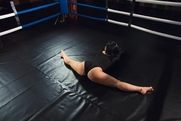 Dziewczyna siedzi na ringu bokserskim. Sexy dziewczyna w strój kąpielowy body jest rozciągnięty w siłowni — Zdjęcie stockowe
