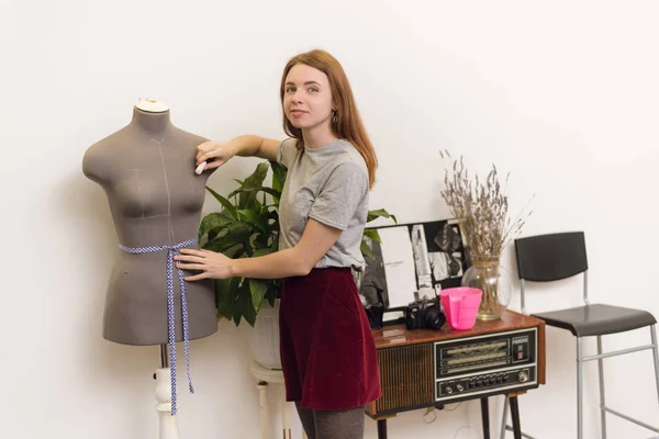 Швея делает измерения с мелом на манекене в офисе. Простаивающая девушка в швейной мастерской — стоковое фото