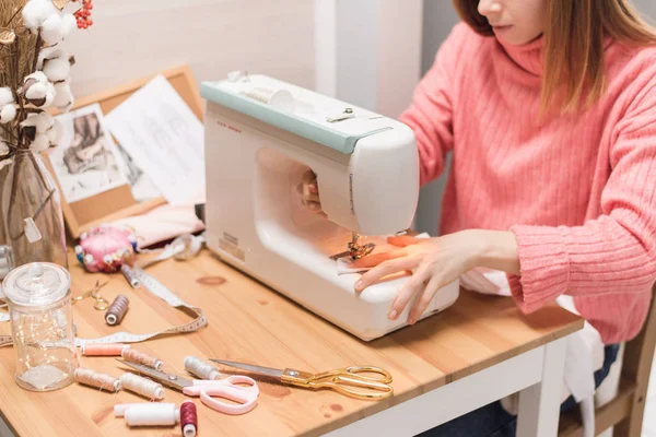 La couture fonctionne sur une machine à coudre. La fille coud et tient un tissu rose — Photo