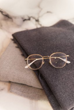 Image glasses on the background of gray scarves. Glasses for the office, stylish autumn scarves