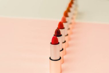 farklı rujlar bir sürü bej ve pembe arka plan üzerinde durmak. Desen ve güzellik kavramı, kozmetik, kadın aksesuarları. Ruj tüplerinin tonları