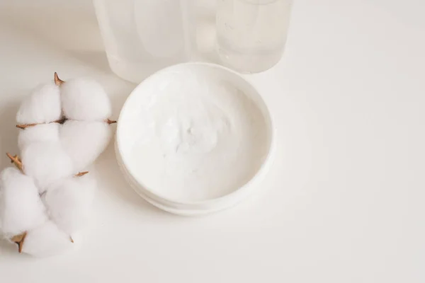 Moisturizer cream next to cotton flowers. White cosmetic bottle containers with cotton flowers on white background top view flat lay. Natural organic beauty product concept, Minimalism style — 스톡 사진