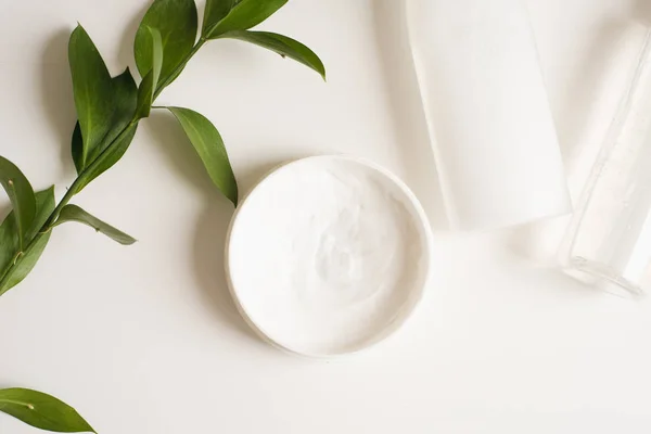 Means for skin care, rejuvenation and hydration of the face. Cream, micellar water and moisturizing lotion on a white background with a branch of green . The philosophy of self care and skin care — Stock Photo, Image