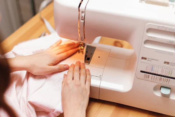 La couture fonctionne sur une machine à coudre. La fille coud et tient un — Photo