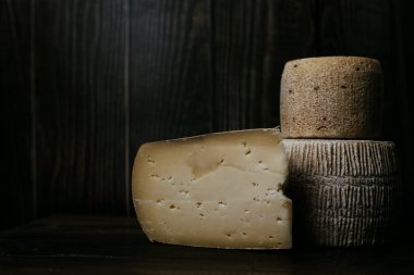 Koyu ahşap bir tahtanın üzerinde Gorgonzola ve kravot 'un yanında manchego peyniri. Alçak tonda peynir fotoğrafçılığı. İnek ve keçi sütünden yapılan doğal yumuşak peynir.