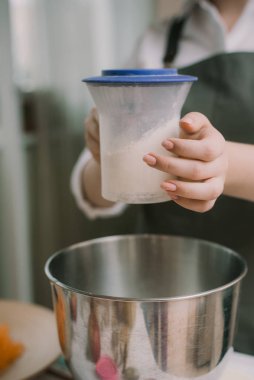 Mutfakta önlüklü bir aşçı unu metal bir kâseye karıştırıyor. Yemek hazırlığı. Dikey