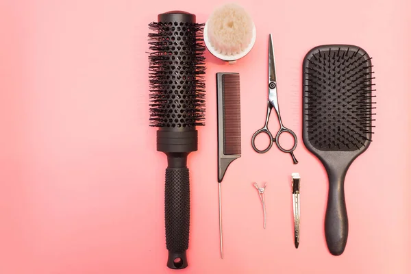 Flat lay composition with hairdresser set on pink background. Barber set with tools and equipment: scissors, combs and hairclips with copy space for text in left. Hairdresser and beauty salon service