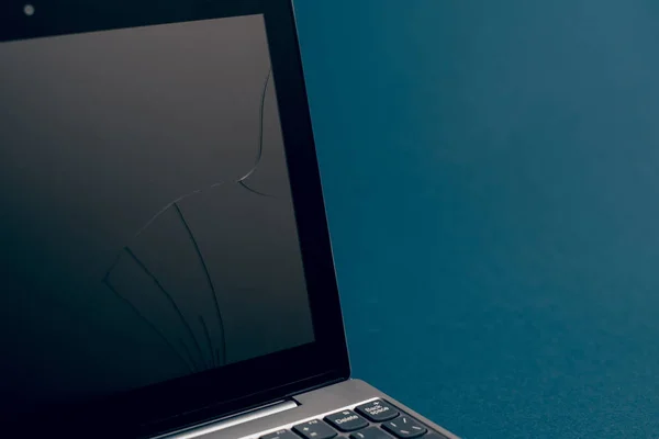 Laptop się popękał i został uszkodzony. Srebrny laptop z zepsutym tabletem z popękanym wyświetlaczem. Zbliżenie obraz części zepsutego laptopa i pęknięty ekran na klasycznym niebieskim tle — Zdjęcie stockowe