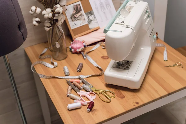 Der Arbeitsplatz einer Näherin. Nähmaschine auf dem Tisch, Garn, Schere und Schaufensterpuppe — Stockfoto