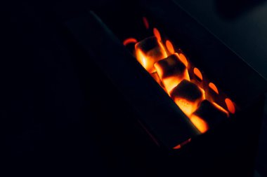 the coals are heated on the tile. Hot ginger coconut coals heat on a hot surface. Preparation of coal for a hookah