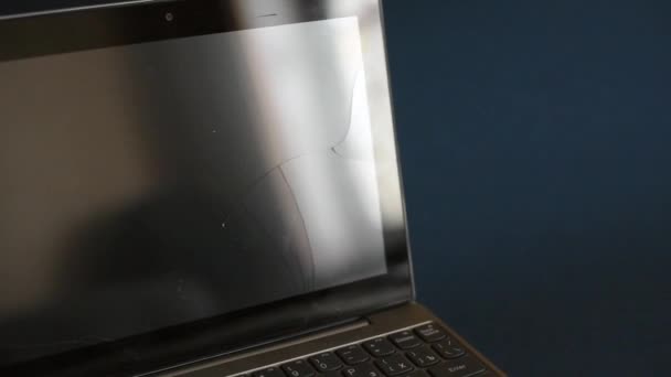 O laptop tela rachado e danificado. Um laptop prateado com um tablet quebrado com uma tela rachada. Uma imagem de close-up de parte do laptop quebrado e tela rachada em um fundo azul clássico — Vídeo de Stock