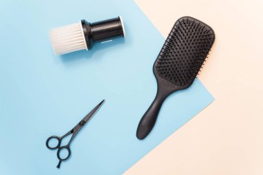 Flat lay composition with professional hairdresser tools on pastel color blue and beige background. Tools for hair styling. Brush for brushing hair, comb for combing and scissors for cutting on a past