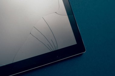 Modern tablet on a classic blue background with cracks. Broken screen of a tablet, smartphone or laptop. Repair concept. Copyspace