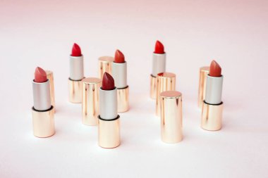 Pembe pastel arka plan üzerinde pembe standı farklı tonlarında birçok lüks altın rujlar