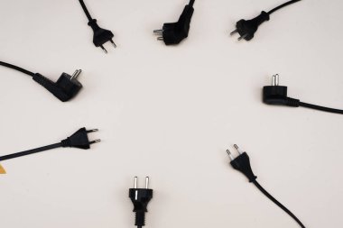 Wires with plugs lie on a white background in a circle. The concept of electricity, energy saving, the choice of electrical appliances and safety. Copyspace, flat lay