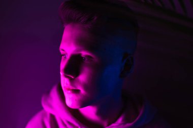 Neon ışıklı genç adam. Pembe kapüşonlu bir genç. Pembe, mor ve mavi renkli.