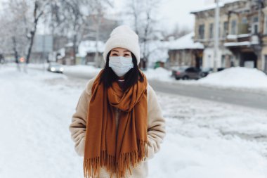 Dışarıda koruyucu maske takan Asyalı bir kız var. Kışın sokakta gezen bir kadın solunum yolunu koronavirüs salgınından korur. Kentsel duman ve toza karşı koruma
