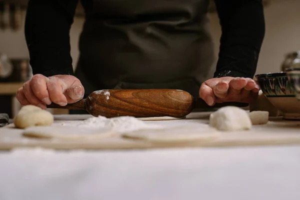 Una donna adulta rotola pasta nella sua cucina per preparare cottura o gnocchi, manti — Foto Stock