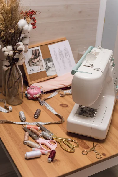 O local de trabalho de uma costureira. Máquina de costura na mesa, linha, tesoura — Fotografia de Stock