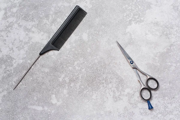 Uma escova de cabelo de separação e tesoura de cortar o cabelo em um fundo cinza de grunge com o lugar do texto. Conjunto de cabeleireiro. Espaço de cópia — Fotografia de Stock