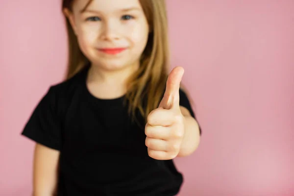 Niña muestra el pulgar hacia arriba sobre un fondo rosa. Plantilla para tu anuncio — Foto de Stock