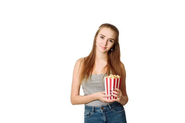 美しいブロンドの女の子はポップコーンを食べ、白い背景に隔離されたコメディア映画を見る。スペース、ブログや広告のテンプレートをコピーします。女ホールドポップコーンと腕時計でカメラ — ストック写真