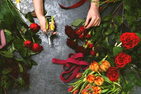 Uma mulher recolhe um buquê de flores de primavera em uma mesa de pedra. Florista do local de trabalho — Fotografia de Stock