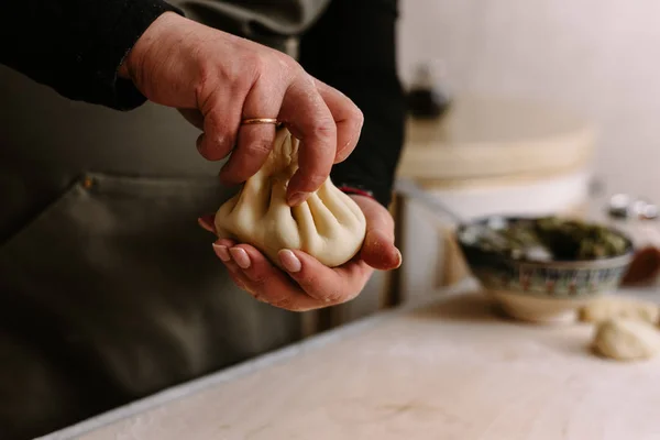 Process cooking. Woman making khinkali for his family close-up. Preparing georgian traditional meal of dough and meat at kitchen. National cuisine, cooking process concept.