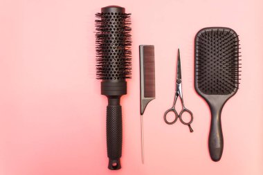 Profesyonel siyah tarak ve makas. Pembe pastel arka planda kuaför aletleri. Farklı amaçlar için farklı saç fırçaları.