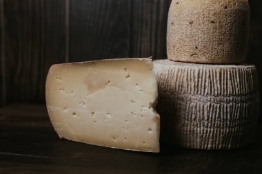 Koyu ahşap bir tahtanın üzerinde Gorgonzola ve kravot 'un yanında manchego peyniri. Alçak tonda peynir fotoğrafçılığı. İnek ve keçi sütünden yapılan doğal yumuşak peynir..