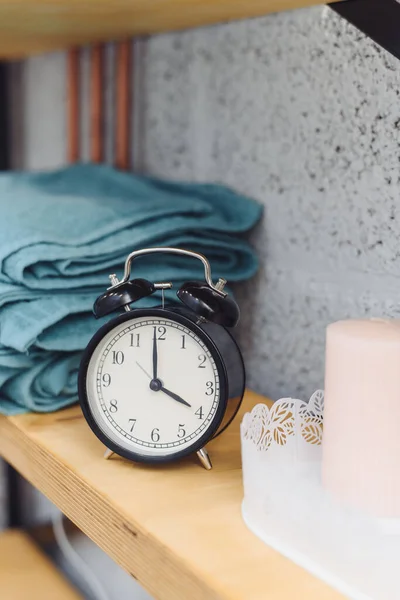 Massage time Analog black clock on a shelf with blue towels and wax candles. The concept of massage items.