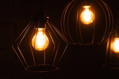Göz kamaştırıcı bir lambanın yakın çekimi. Turuncu ışıklı ampul. Büyük bir dekoratif spiral ile parlak bir edison lamba yakmak..