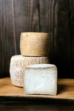 Hard cheese kravot or parmesan on a wooden dark board. Cheese knife next to the cheese heads.