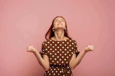 Pembe stüdyo arka planında beyaz kadın modelinin dinamik görüntüsü. Kazanan mutlu kadın, kazanan olmayı kutluyor. Zafer, zevk konsepti. İnsan yüz duyguları konsepti. Moda renkleri.
