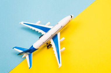 Çevrimiçi seyahat rezervasyonu. Sarı ve mavi arka planda uçak modeli ve pasaport. Soyut pist.