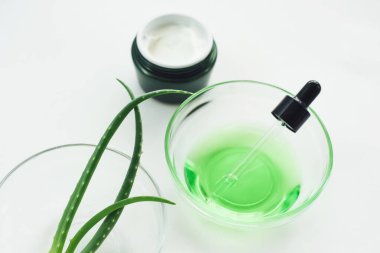Aloe jeli, aloe vera yaprakları ve beyaz arka plandaki doğal malzemelerden yeşil serum. Evde kozmetik yapıyorum..