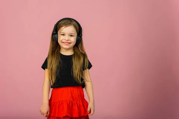 Ένα Μικρό Κορίτσι Ασύρματα Μεγάλα Μαύρα Ακουστικά Ροζ Παστέλ Φόντο — Φωτογραφία Αρχείου