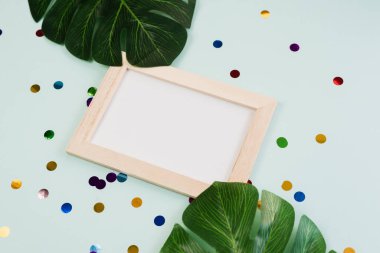 İçinde konfeti olan mavi bir arka planda mesaj ya da reklam için boş bir yer olan fotoğraf çerçevesi. Tropik hafta sonu partisi.