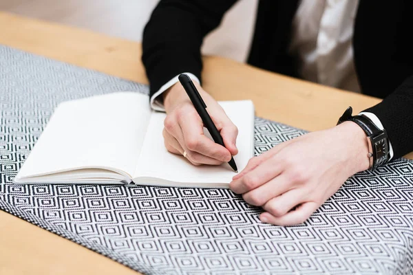 Man hand with pen writing on notebook. Concept of a businessman writing on a notebook. Image can be used for background, website banner, promotional materials, presentation templates, advertising and printed materials.