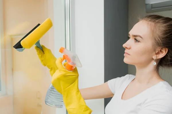 Schattig Volwassen Meisje Wast Een Raam Met Een Schraper Voorjaarsschoonmaak — Stockfoto