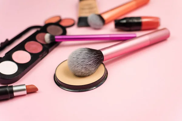 化粧品には様々な化粧品があります フェイスパウダー ブラシ ピンクの背景にメイクのための様々な化粧品の装飾品 — ストック写真