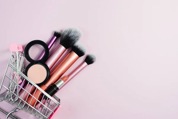 購入者のピンク色のトロリーの目の影赤面 口紅や様々なメイクブラシ オンラインショッピング装飾化粧品の概念 店舗での割引 — ストック写真