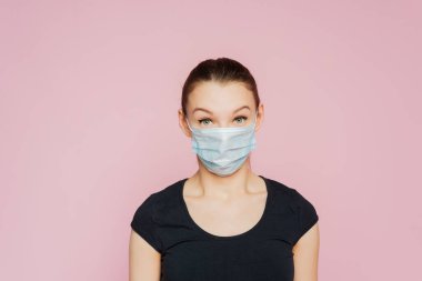 Stüdyo portresi, yüz maskesi takan, kameraya bakan, pembe arka planda izole edilmiş, yakın plan. Grip salgını, toz alerjisi, virüse karşı koruma. Covid-19, koronavirüs salgını.