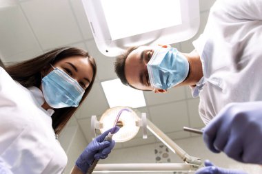 Adam neşeyle aşağıya bakıyor. Hastanın bakış açısından dişçiye muayene.