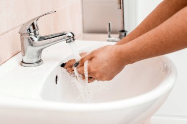 Umumi bir yerdeki lavaboda sabunla el yıkama. Hijyen konsepti. Musluğun altında sabunla ellerini yıkamak, suyla..