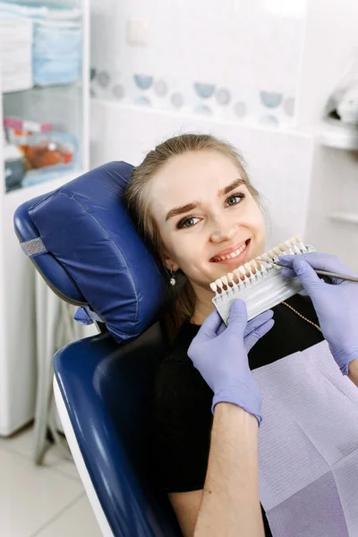 歯医者は美しい少女患者を白くするために歯のエナメル質の色を選択します 歯の色を選び — ストック写真
