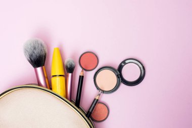Pembe bir makyaj çantasından pembe bir arka plana dökülen makyaj ürünlerinin genel görünümü. güzellik, moda ve alışveriş konsepti.