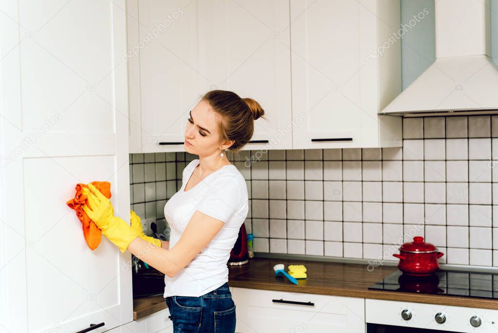 Attractive worker stands at cupboard and clean it. Girl smiles. people, housework and housekeeping concept.