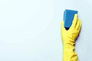 Sarı lastik eldiven beyaz arka planda sünger tutuyor. Sarı lastik eldiven süngerle temizleniyor..
