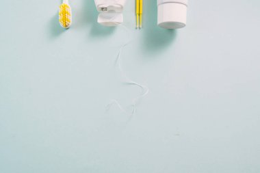 Sarı diş fırçası, iplik, diş macunu ve pamuk tomurcukları mavi arka planda reklamınız için bir yer. Diş bakımı ve diş temizliği kavramı.